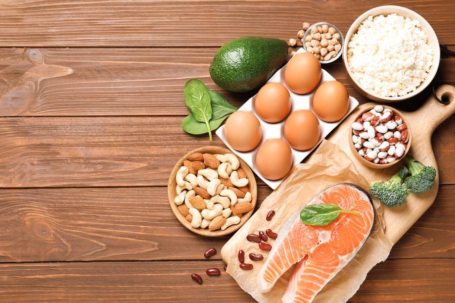Nerve-healthy foods including salmon, eggs, nuts and leafy greens on wooden surface