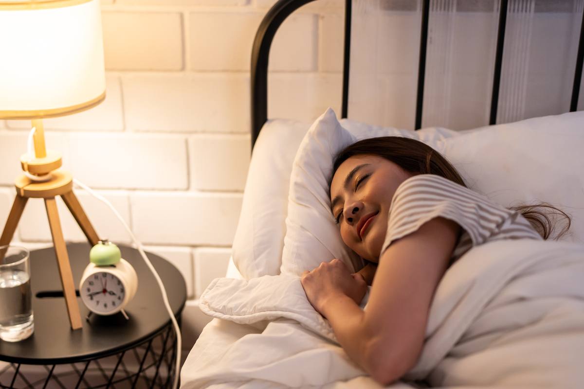 Woman sleeping peacefully with alarm clock — sleep health for women